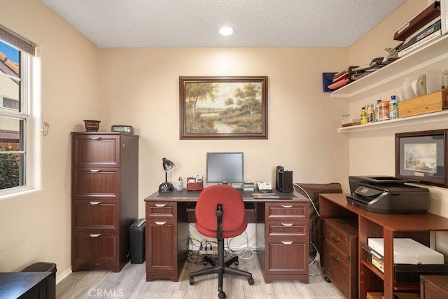 office space featuring light wood finished floors, a textured ceiling, and baseboards