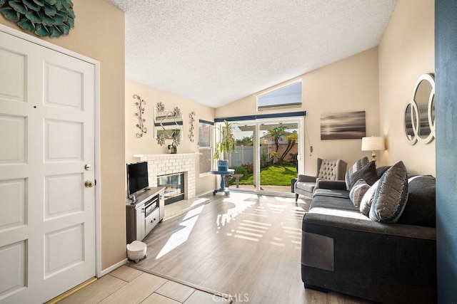 living area featuring baseboards, vaulted ceiling, a fireplace, wood finished floors, and a textured ceiling