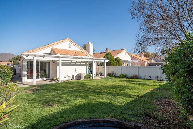 rear view of house featuring stucco siding, a pergola, a fenced backyard, a yard, and a tiled roof