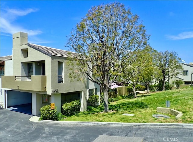 view of side of property with a balcony, a garage, and a lawn