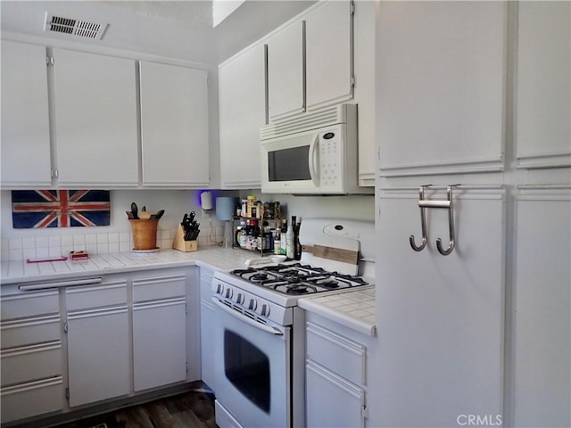 kitchen with tile countertops, white cabinetry, dark wood-type flooring, and white appliances