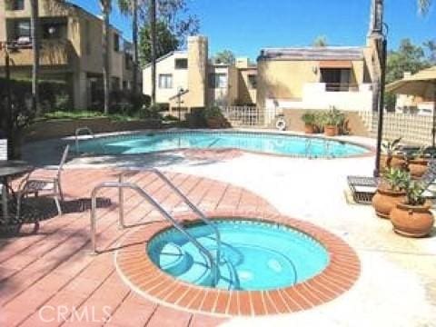 view of pool featuring a community hot tub and a patio