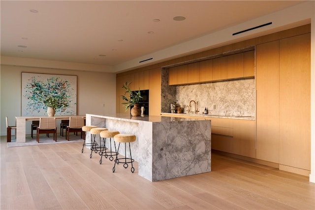 bar featuring sink and light hardwood / wood-style flooring