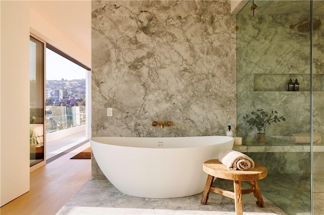 bathroom with hardwood / wood-style flooring and a tub to relax in