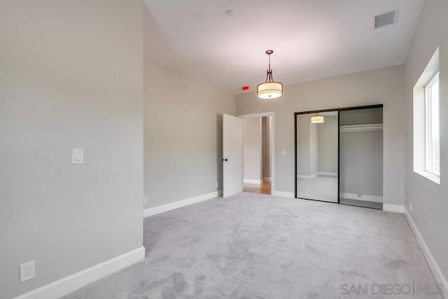 unfurnished bedroom with a closet and light colored carpet