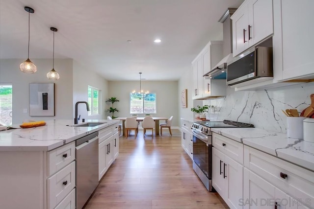 kitchen with an inviting chandelier, hanging light fixtures, sink, appliances with stainless steel finishes, and white cabinetry