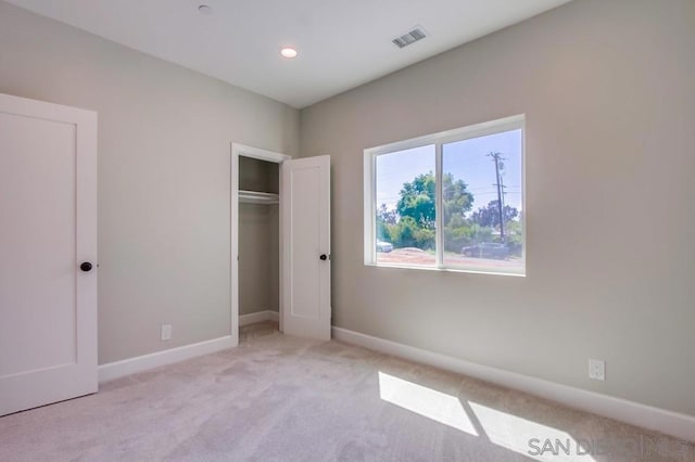 unfurnished bedroom featuring light colored carpet and a closet