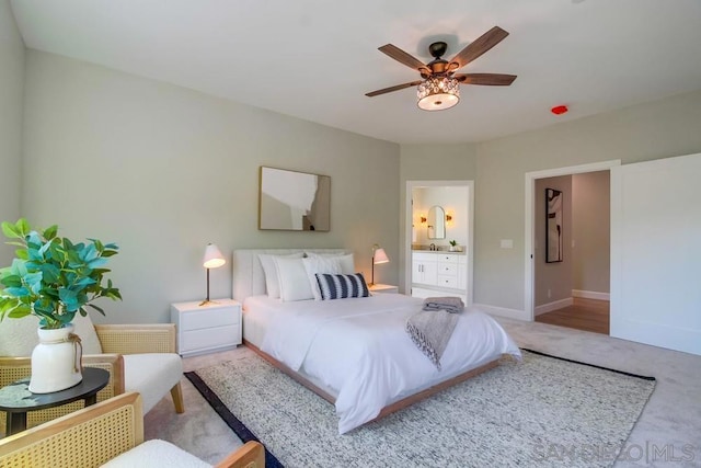 bedroom featuring ceiling fan, light colored carpet, and connected bathroom