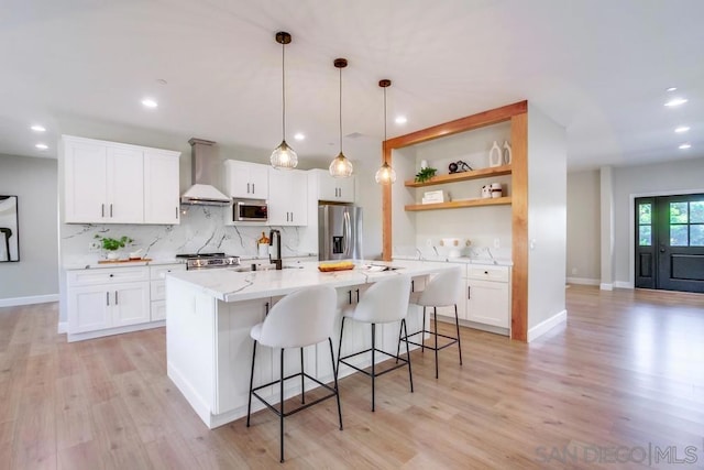 kitchen featuring stainless steel appliances, white cabinetry, wall chimney exhaust hood, and sink