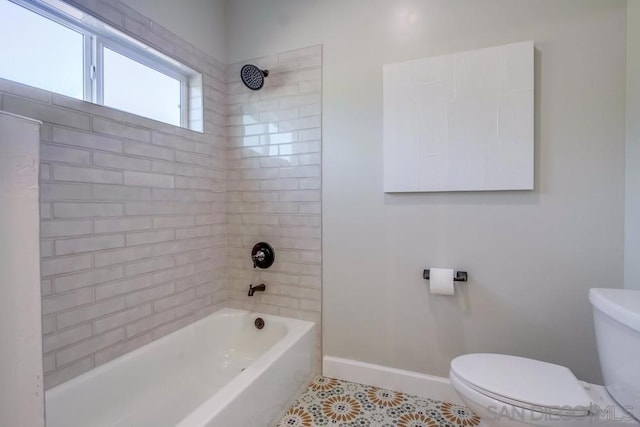 bathroom featuring tile patterned flooring, toilet, and tiled shower / bath