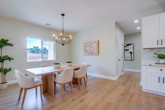 dining room with light hardwood / wood-style floors and an inviting chandelier