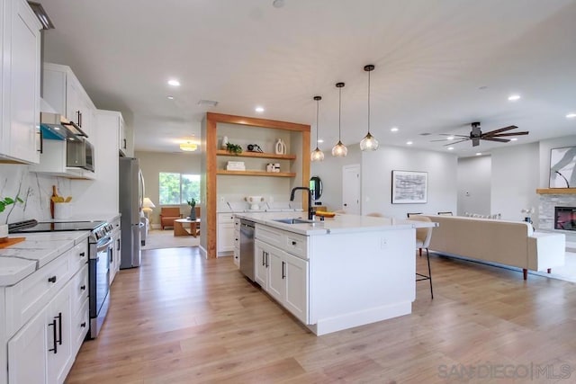 kitchen with stainless steel appliances, white cabinetry, a kitchen island with sink, and sink