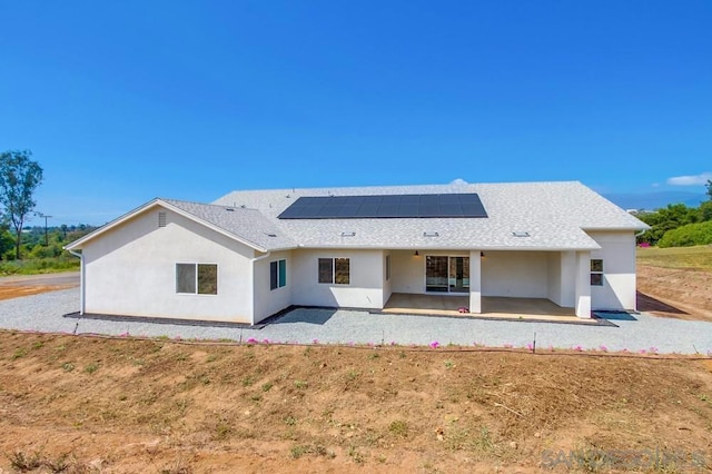 back of property with solar panels and a patio area