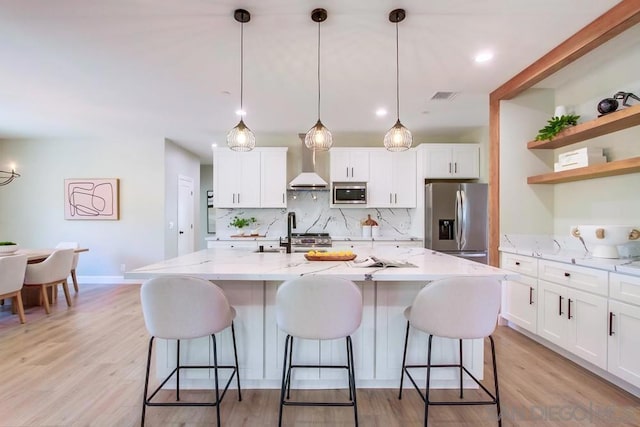 kitchen featuring light stone countertops, appliances with stainless steel finishes, sink, decorative light fixtures, and white cabinets