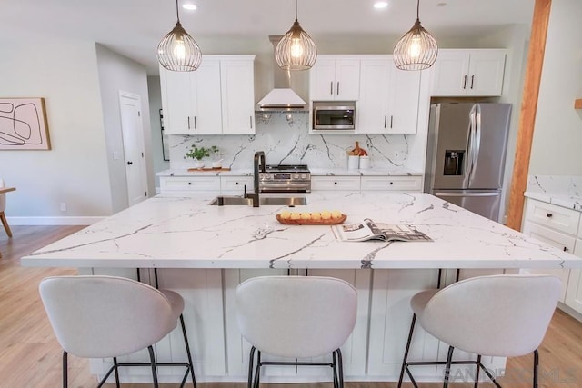 kitchen with a center island with sink, sink, appliances with stainless steel finishes, tasteful backsplash, and white cabinetry