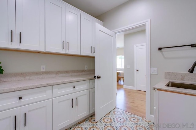 kitchen featuring white cabinetry, sink, and light stone countertops