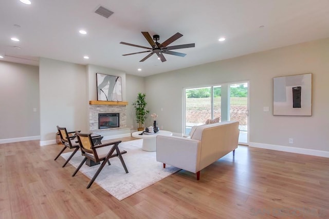 living room with ceiling fan, a fireplace, and light hardwood / wood-style flooring