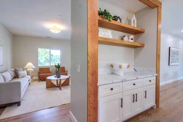 kitchen featuring white cabinetry, light stone counters, and light hardwood / wood-style floors