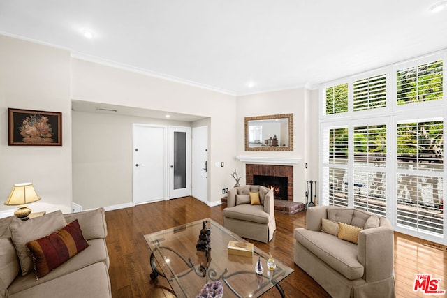 living room featuring wood-type flooring, a brick fireplace, and crown molding