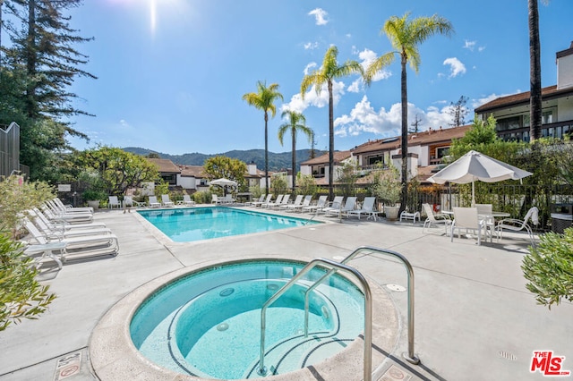 view of swimming pool with a mountain view, a patio, and a hot tub