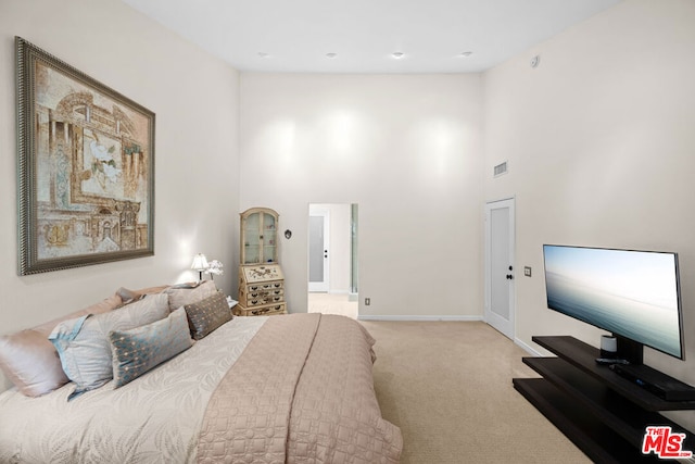 bedroom featuring a towering ceiling and light colored carpet