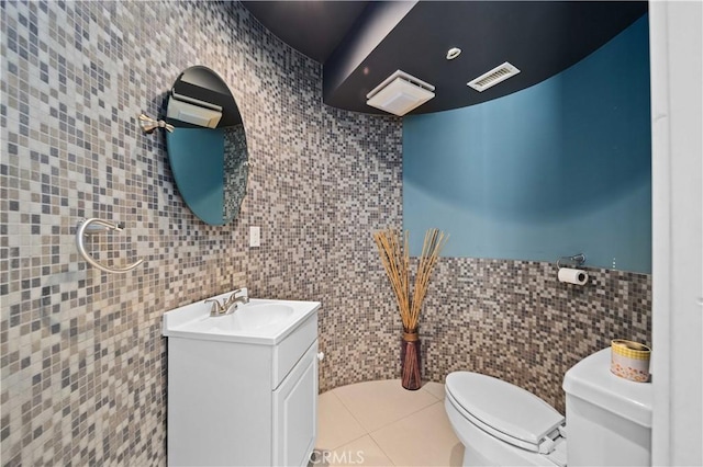 bathroom with toilet, vanity, tile patterned floors, and tile walls