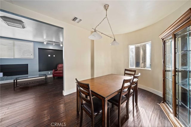 dining room with dark hardwood / wood-style floors and rail lighting