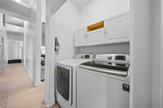 washroom with washer and clothes dryer, light tile patterned floors, and cabinets