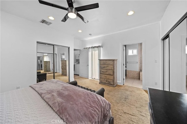 carpeted bedroom with connected bathroom, ceiling fan, washer and dryer, and multiple closets