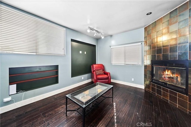 sitting room with a tile fireplace, hardwood / wood-style flooring, and tile walls