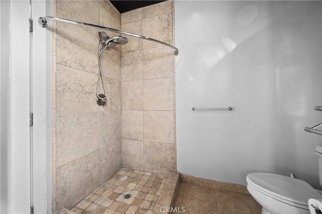 bathroom featuring a tile shower, tile patterned floors, and toilet