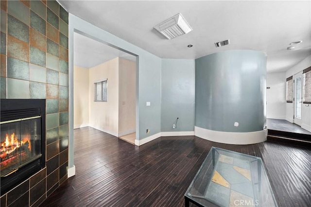 living room featuring dark hardwood / wood-style flooring and a tiled fireplace