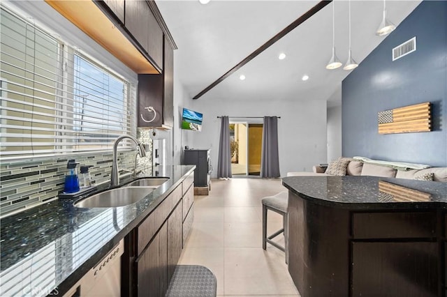 kitchen featuring sink, tasteful backsplash, dark stone countertops, lofted ceiling, and dark brown cabinets