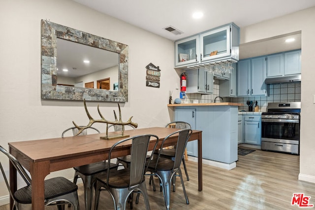 kitchen featuring stainless steel range, kitchen peninsula, blue cabinets, and light hardwood / wood-style flooring