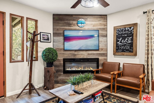 living room featuring hardwood / wood-style flooring, ceiling fan, and a fireplace