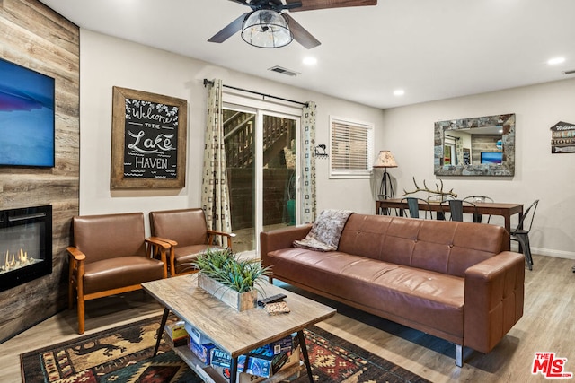 living room with ceiling fan, a fireplace, and light hardwood / wood-style flooring