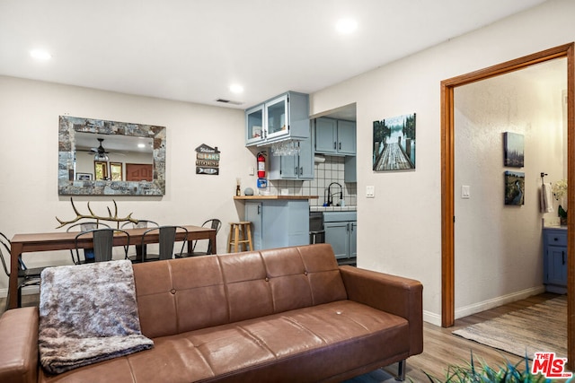 living room with light wood-type flooring, ceiling fan, and sink