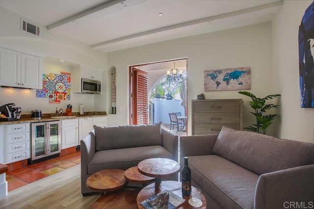 living room featuring beverage cooler, sink, beam ceiling, light hardwood / wood-style flooring, and a notable chandelier