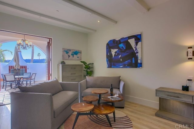 living room featuring beamed ceiling, plenty of natural light, light wood-type flooring, and an inviting chandelier