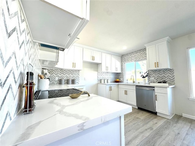 kitchen featuring tasteful backsplash, stainless steel dishwasher, sink, white cabinets, and light hardwood / wood-style floors