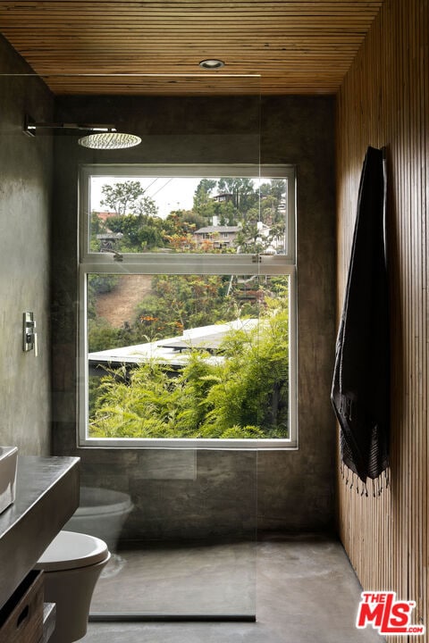 bathroom with walk in shower, concrete floors, toilet, and a bidet