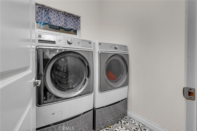 laundry area with light tile patterned floors and washing machine and clothes dryer