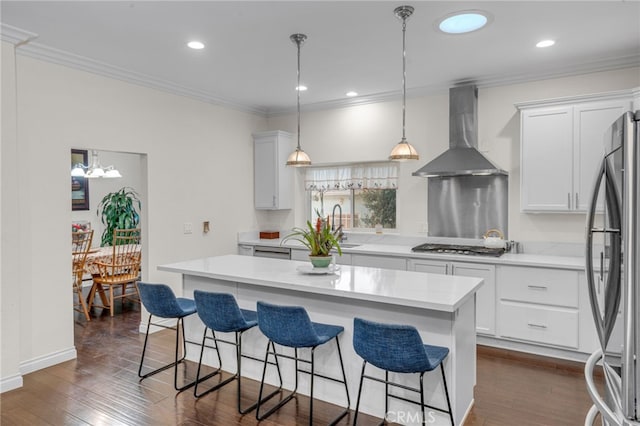 kitchen featuring appliances with stainless steel finishes, wall chimney exhaust hood, white cabinets, dark hardwood / wood-style floors, and a kitchen island