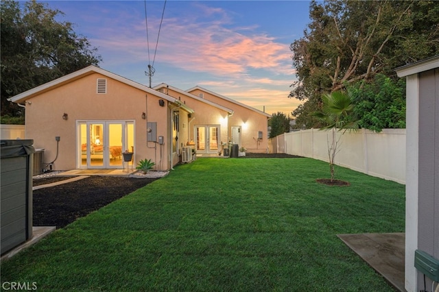 yard at dusk with central air condition unit and french doors