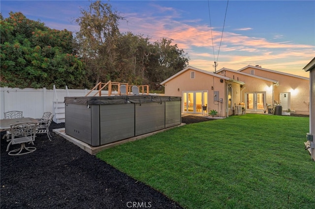 yard at dusk with french doors, central AC, and a swimming pool with hot tub