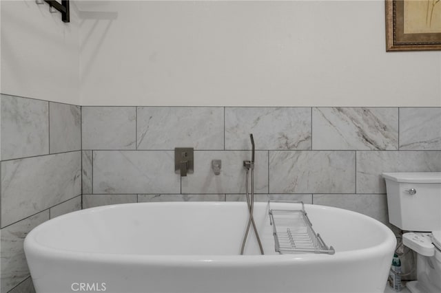 bathroom featuring a tub, tile walls, and toilet