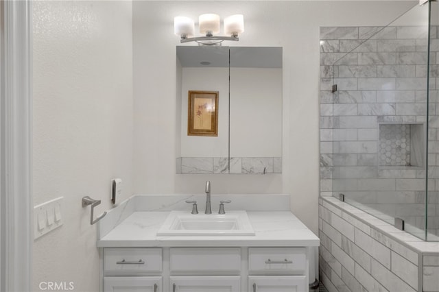 bathroom with a tile shower and vanity