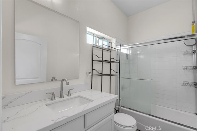 full bathroom with combined bath / shower with glass door, toilet, and vanity