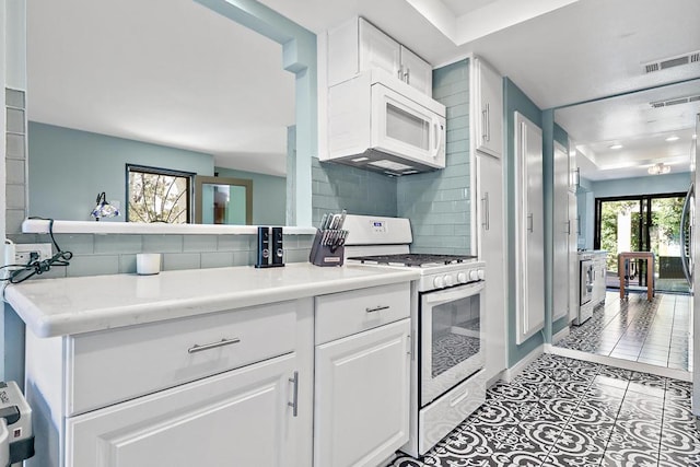 kitchen with tasteful backsplash, white cabinetry, light tile patterned floors, and white appliances