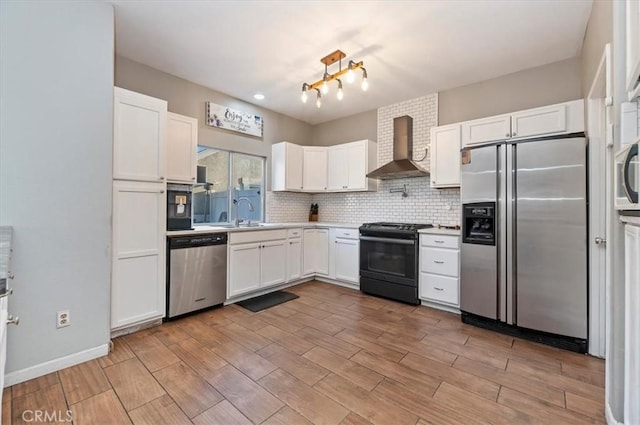 kitchen with wall chimney range hood, decorative backsplash, sink, appliances with stainless steel finishes, and white cabinets